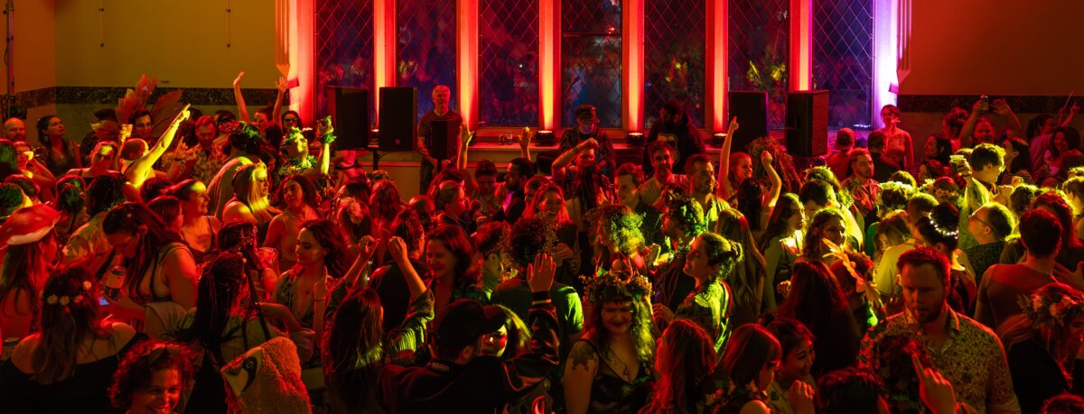 Many people dancing under red and yellow lights.